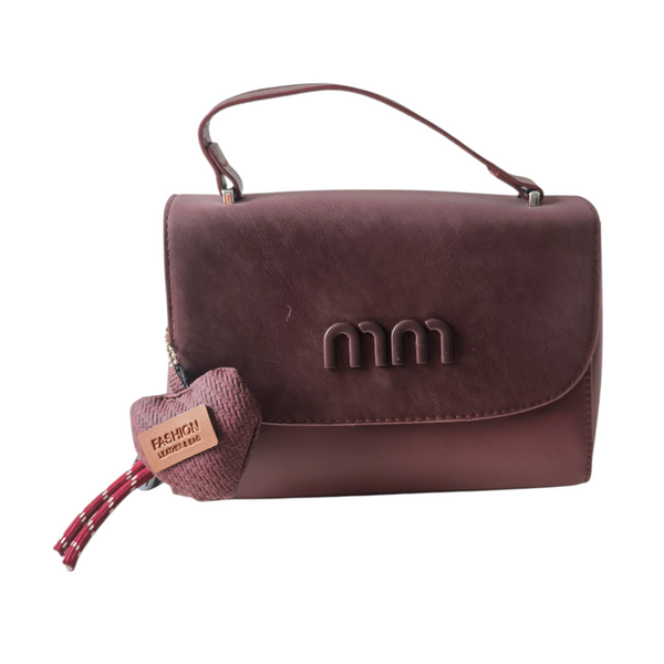 Cartera pequeña ZEFORA color vino con solapa frontal, asa superior y detalle de llavero decorativo en forma de corazón