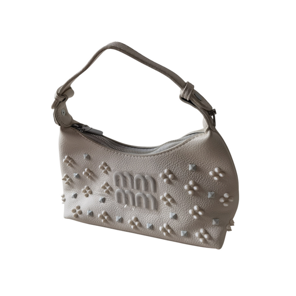 Cartera pequeña ZEFORA color crema con silueta curva, asa superior y detalles decorativos en relieve