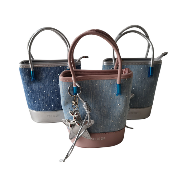 Carteras tipo bucket ZEFORA en tonos azul y rosa con acabado denim, detalles metálicos y colgante decorativo.