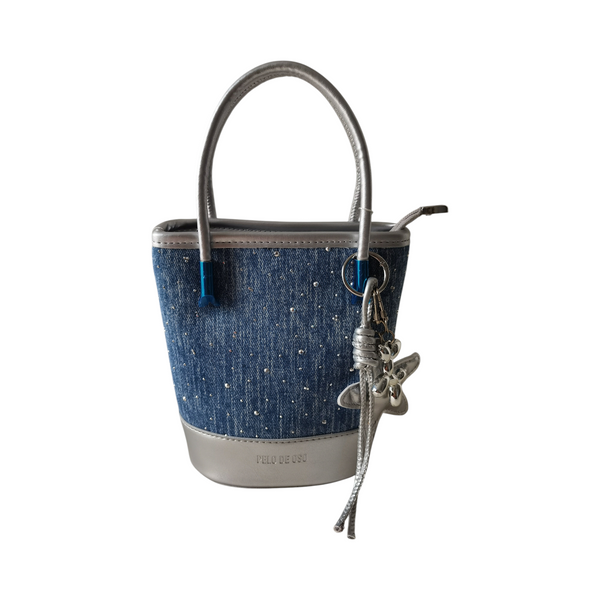 Cartera tipo cubo ZEFORA en denim azul con detalles brillantes, asas plateadas y colgante decorativo