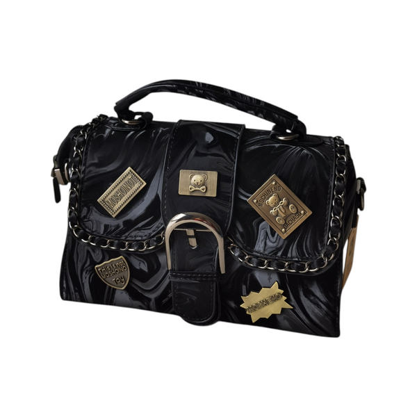 Cartera ZEFORA Dakota negra con acabado brillante, parches metálicos decorativos, cadena y cierre frontal