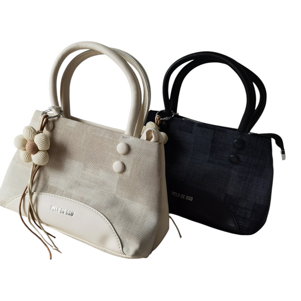 Carteras ZEFORA Isabella en color crema y negro, diseño estructurado con asas redondeadas y colgante de flor.
