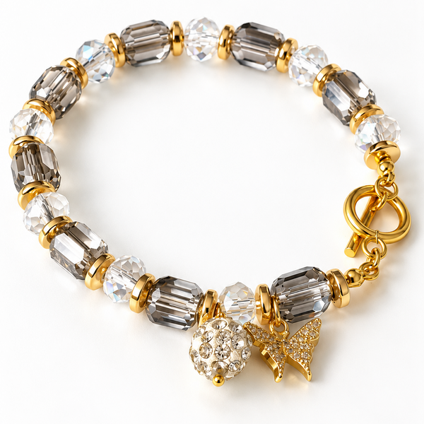 Descubre la pulsera Crystal Butterfly con cristales transparentes y ahumados, detalles dorados y dije de mariposa. Un accesorio elegante y femenino de Zefora Accesorios.